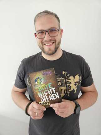 Das Buchcover mit dem Titel Anna in der Wand. Es zeigt ein Bücherregal und ein Loch in der Wand, durch das jemand hindurchsieht. Ein Schmetterling fliegt vorüber.