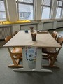 Zu sehen ist ein langer Tisch mit Stühlen. Dort sind Sticker, Stempel und Stifte zum gestalten bereitgestellt.